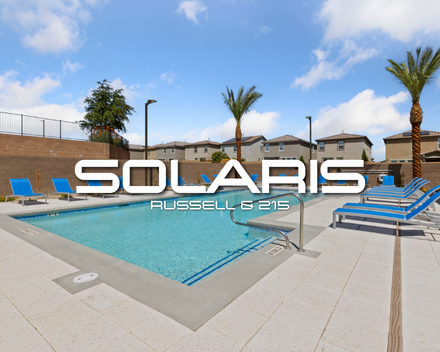 Sparkling community swimming pool surrounded by bright blue lounge chairs and palm trees at the Solaris at Russell new home community in Southwest Las Vegas.