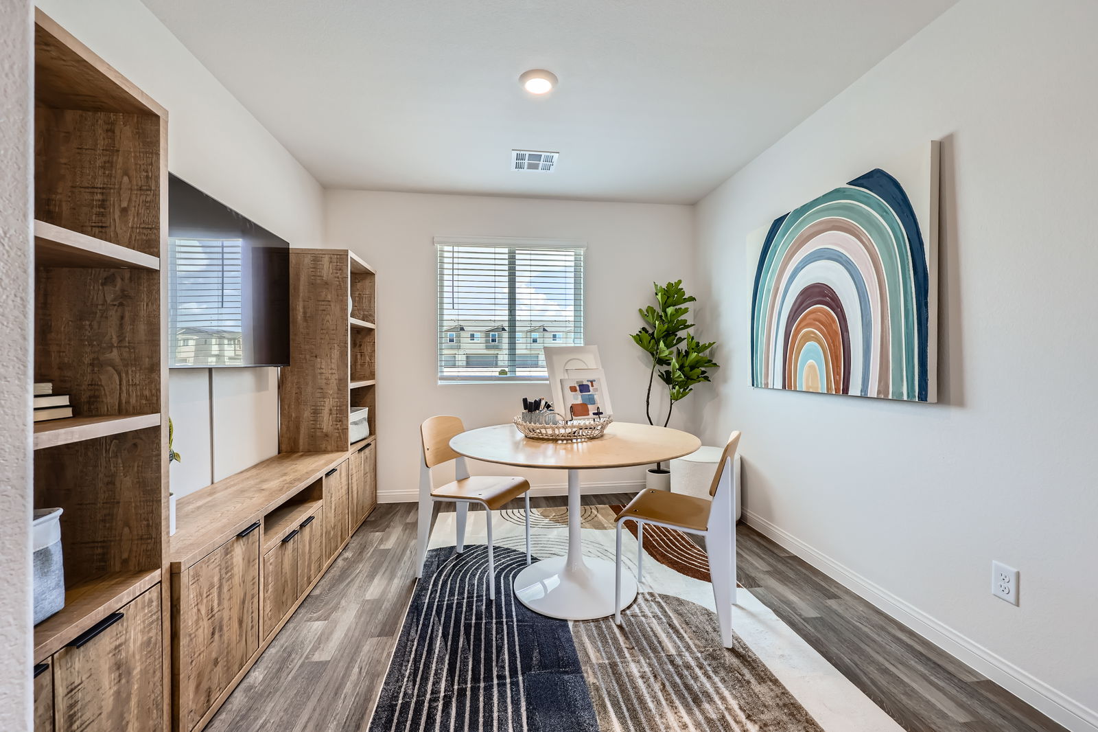Versatile bonus room staged as a creative workspace with a round table, modern chairs, and built-in shelving in a Touchstone Living home.