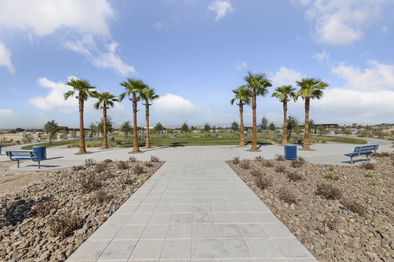 Paved walkway leading into the 5-acre community park with palm trees and green space at the Independence townhome community in East Las Vegas.