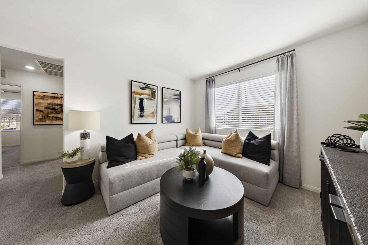 Modern upstairs loft featuring a long grey sofa, a round black coffee table, and contemporary decor in a Touchstone Living home.