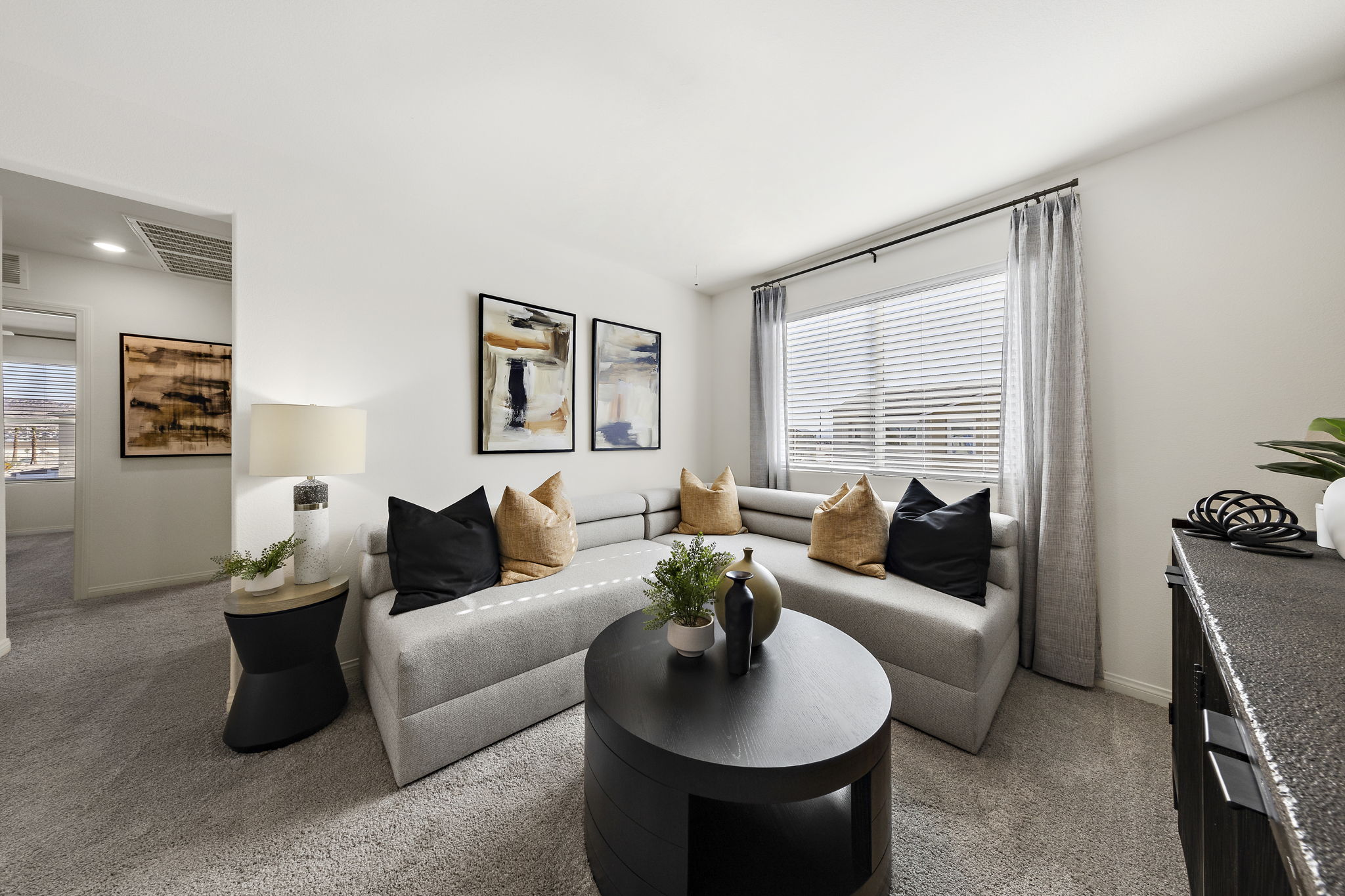 Modern upstairs loft featuring a long grey sofa, a round black coffee table, and contemporary decor in a Touchstone Living home.