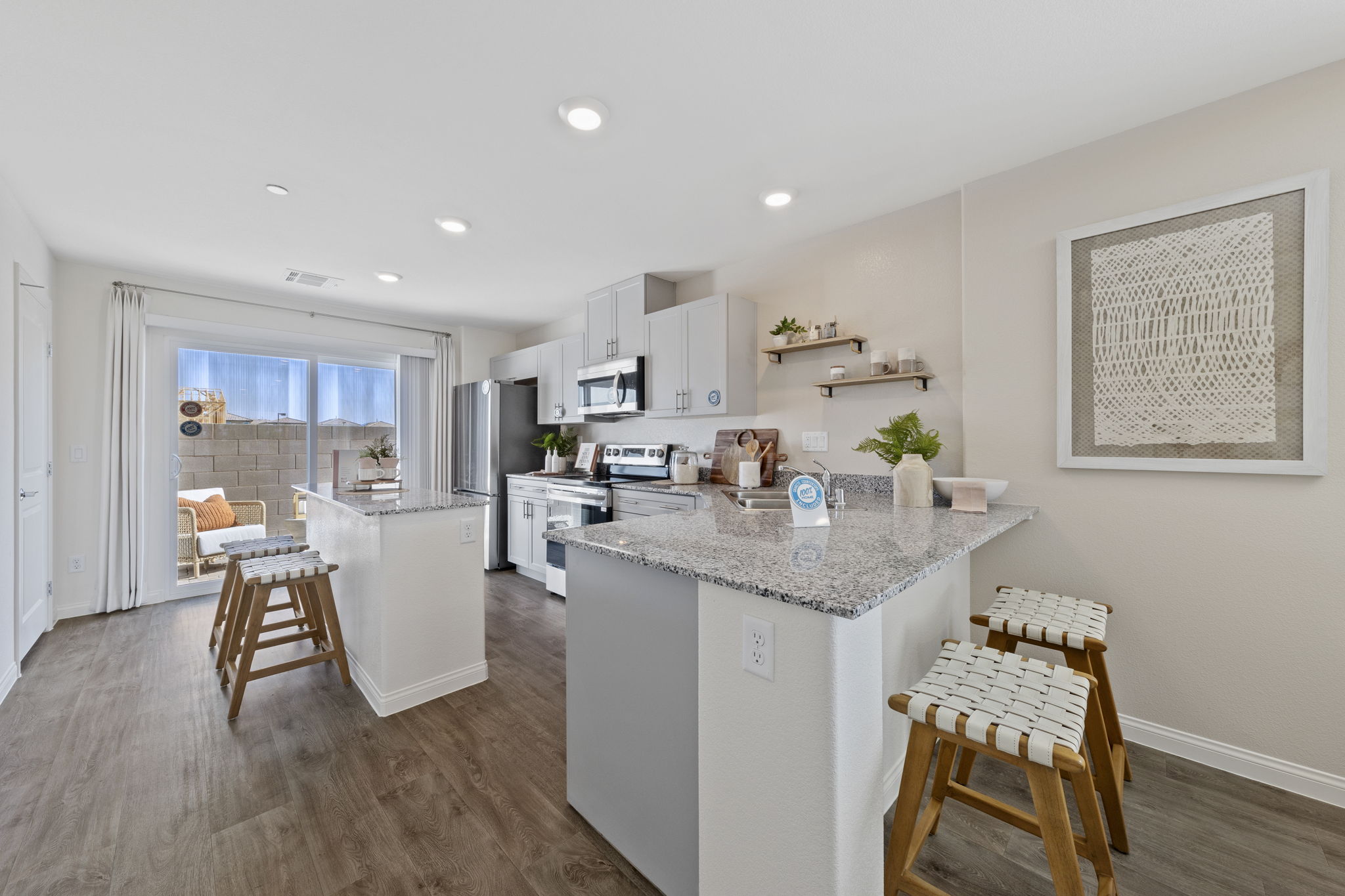 Modern kitchen featuring light grey cabinetry, granite countertops, upgraded vinyl flooring, and stainless steel Samsung® appliances in a Solaris model home.