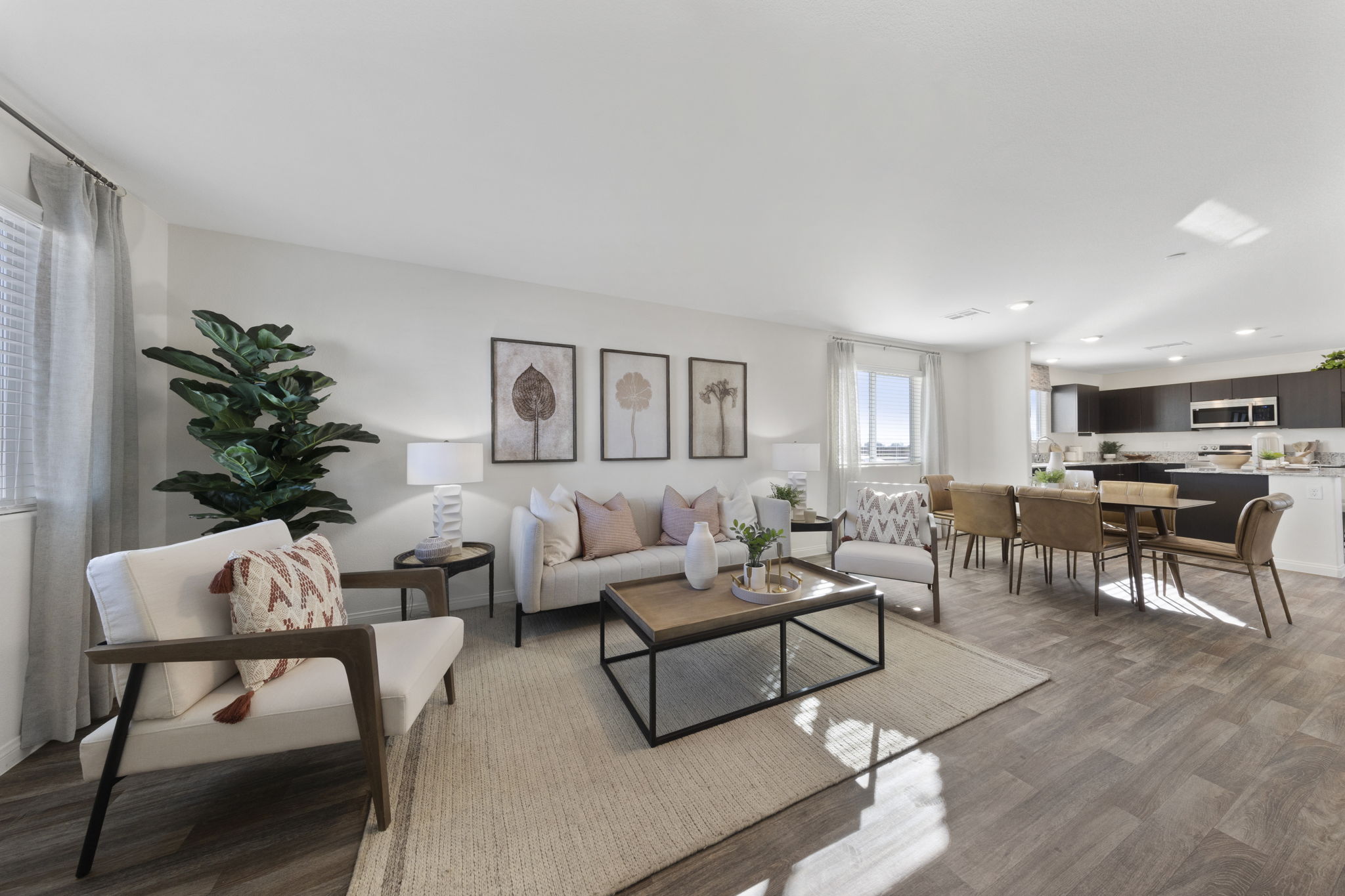 Expansive open-concept living and dining area featuring a light beige sofa, accent chairs, and a large jute rug in a Touchstone Living home at Independence.