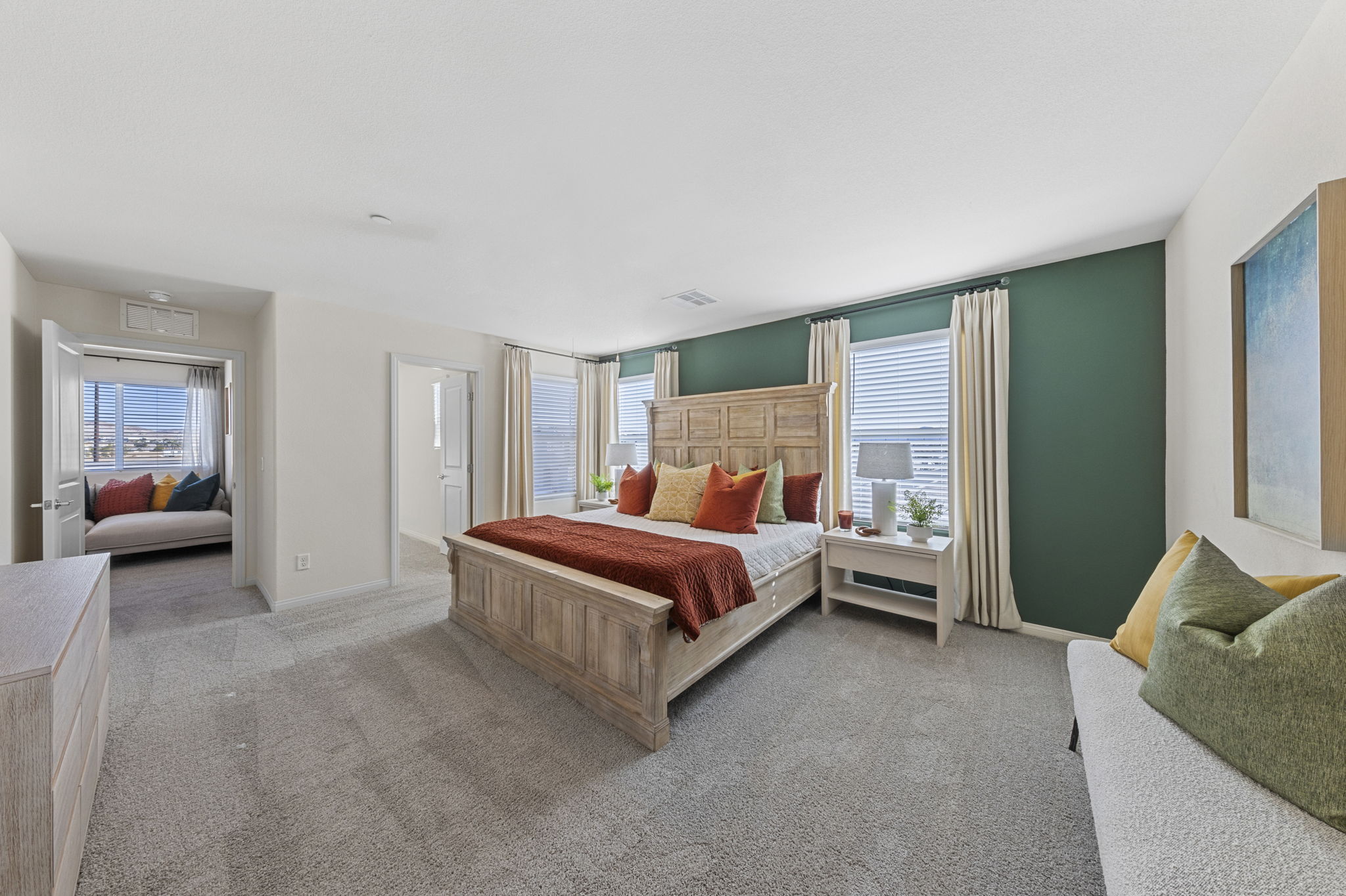 Spacious primary bedroom suite featuring a large wooden bed, a dark green accent wall, and a large walk-in closet in a Touchstone Living home.