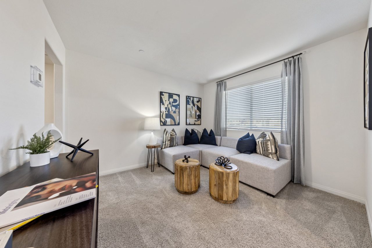 Cozy upstairs loft area staged with a grey sectional sofa and two wooden coffee tables in a Touchstone Living home.