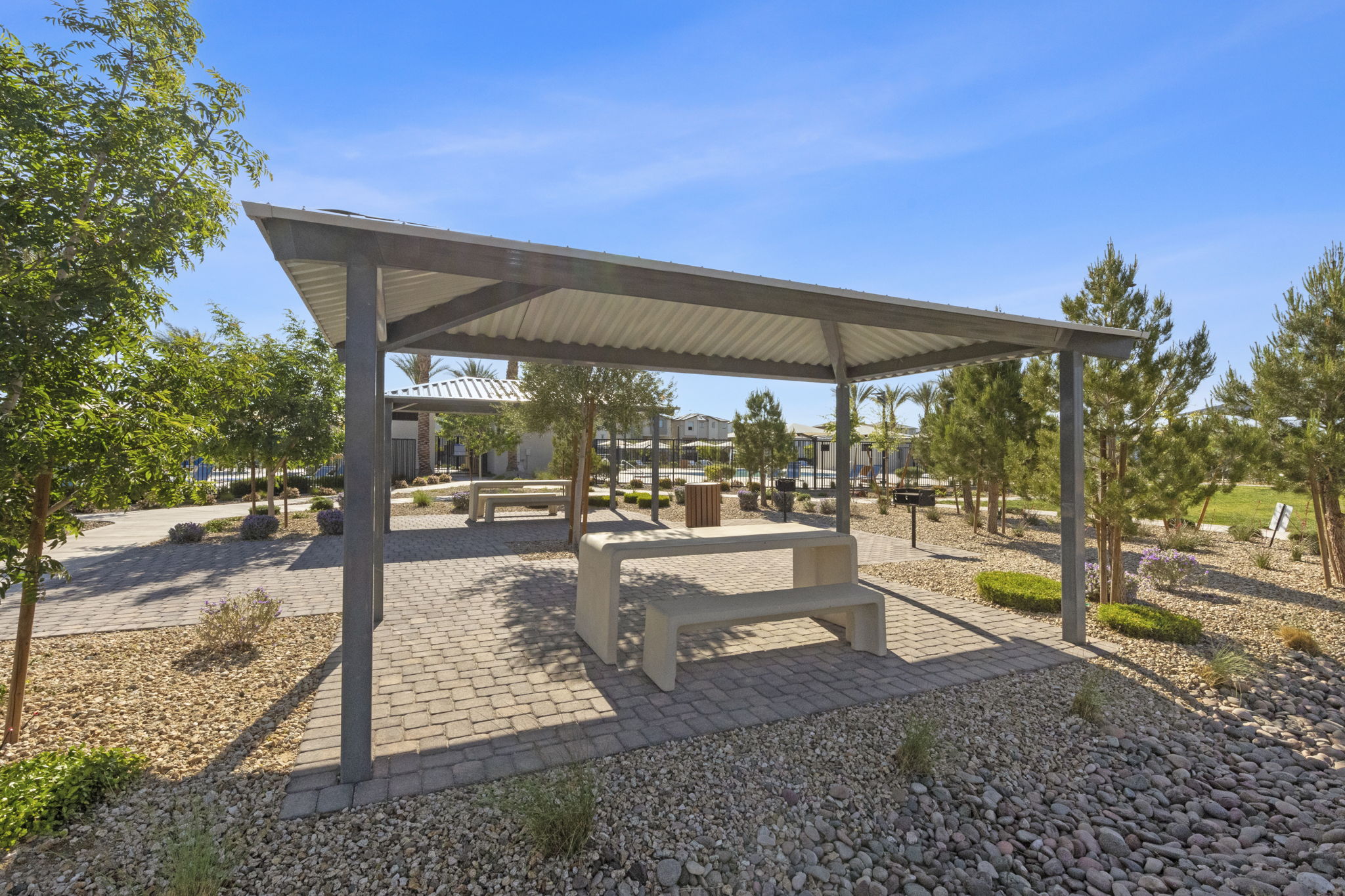 Covered picnic pavilion with a concrete table and benches surrounded by desert landscaping at the Watercolor planned community.