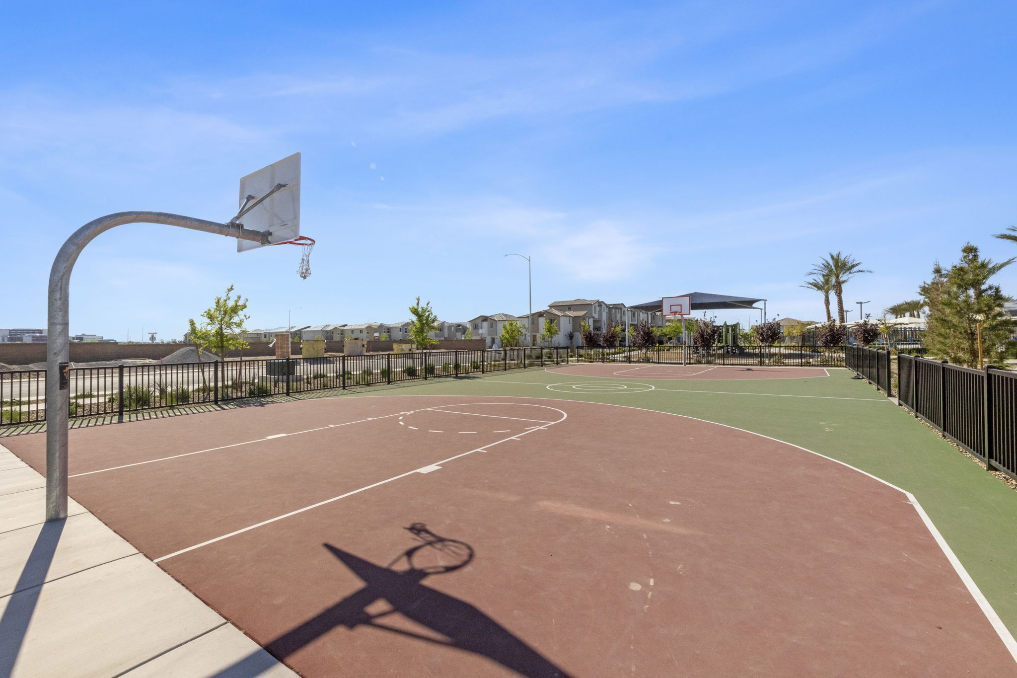 Outdoor basketball court with a red and green painted surface and a metal hoop at the Watercolor planned community.