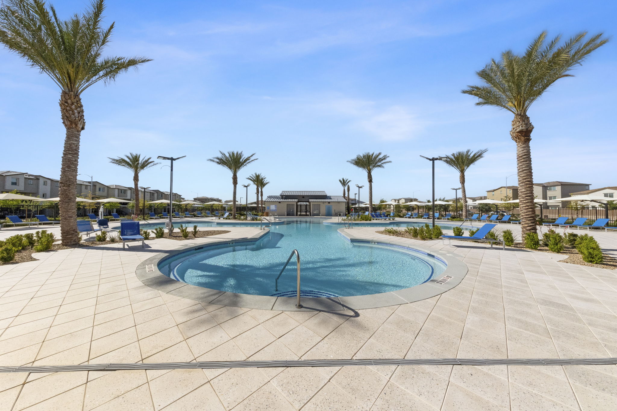 Large, free-form resort-style swimming pool surrounded by palm trees and blue lounge chairs at the Watercolor planned community.