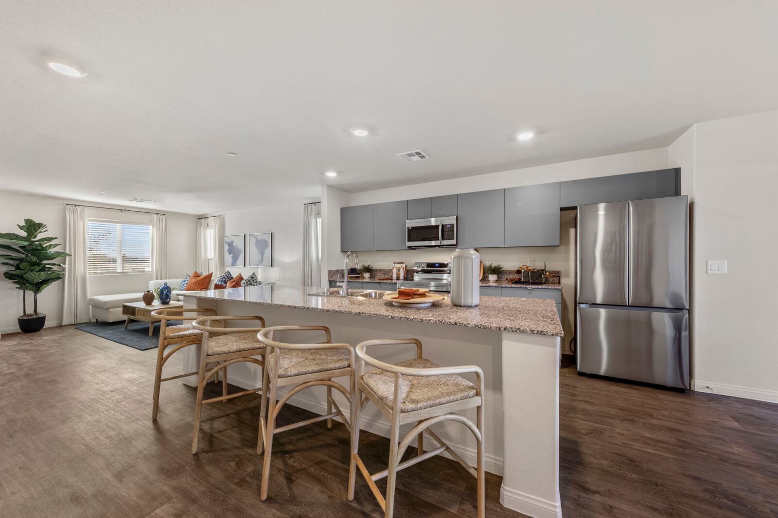 Modern open-concept kitchen with a granite island, grey cabinets, and stainless steel appliances in an affordable townhome at the Independence neighborhood in East Las Vegas.