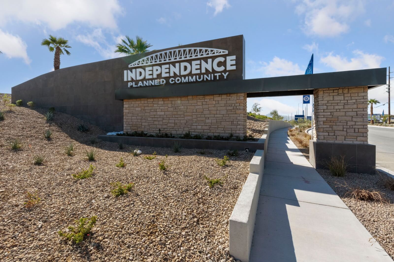 Grand monument sign with stone veneer and desert landscaping confirming the entrance to Independence Planned Neighborhood by Touchstone Living in East Las Vegas.