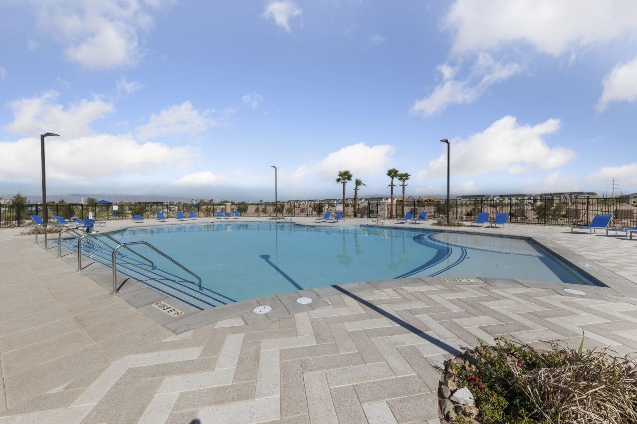 Resort-style swimming pool with shallow entry, blue lounge chairs, and a paved deck at the Independence planned neighborhood in East Las Vegas.