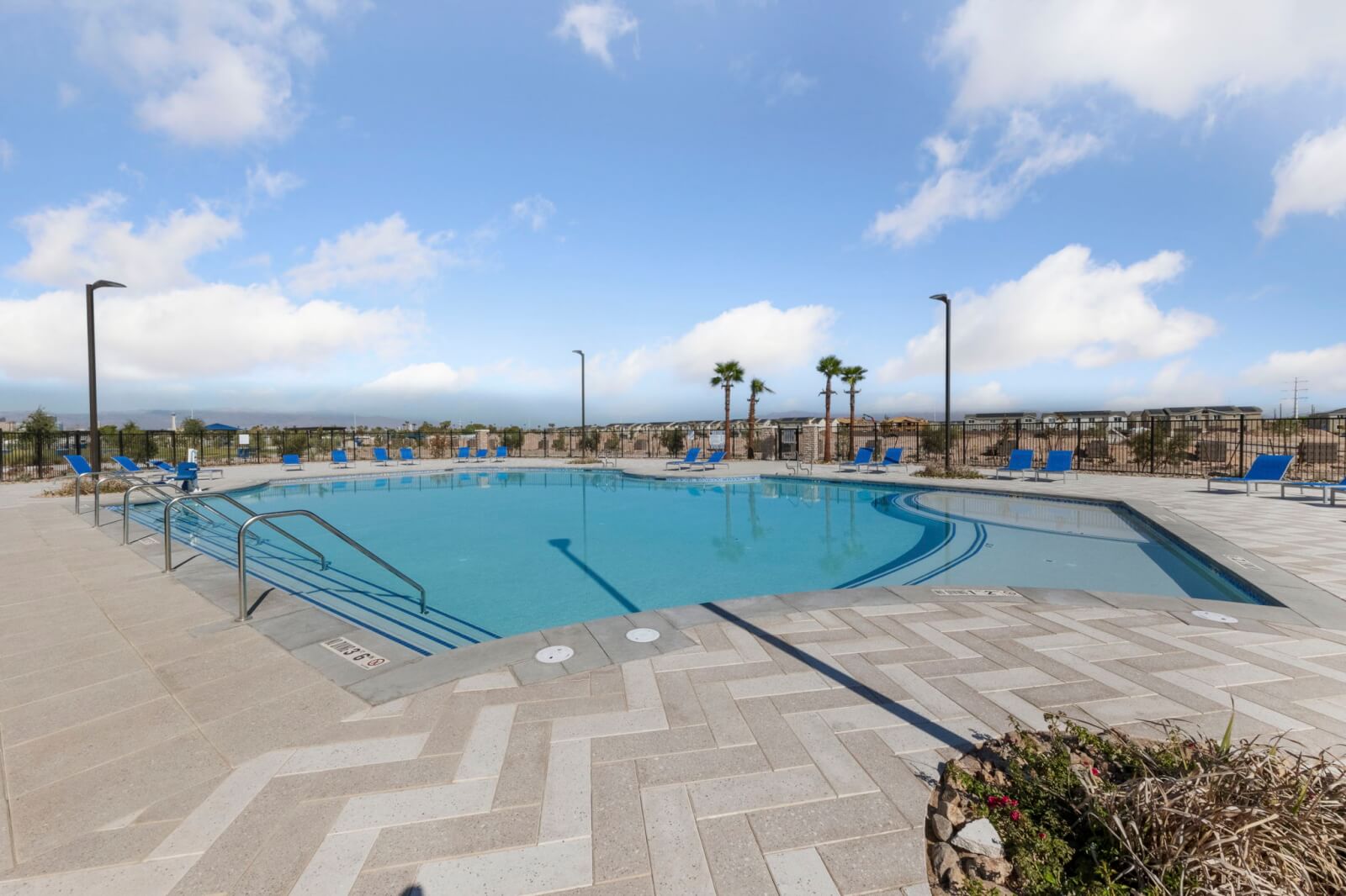 Resort-style swimming pool with shallow entry, blue lounge chairs, and a paved deck at the Independence planned neighborhood in East Las Vegas.