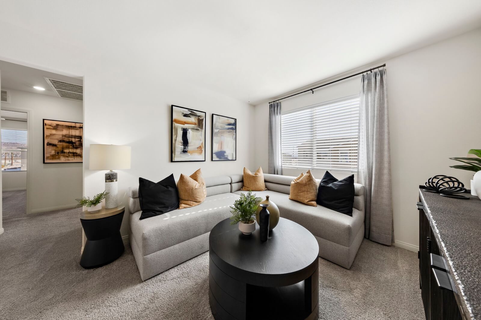 Modern upstairs loft featuring a long grey sofa, a round black coffee table, and contemporary decor in a Prosperity 190 home at the Independence neighborhood.