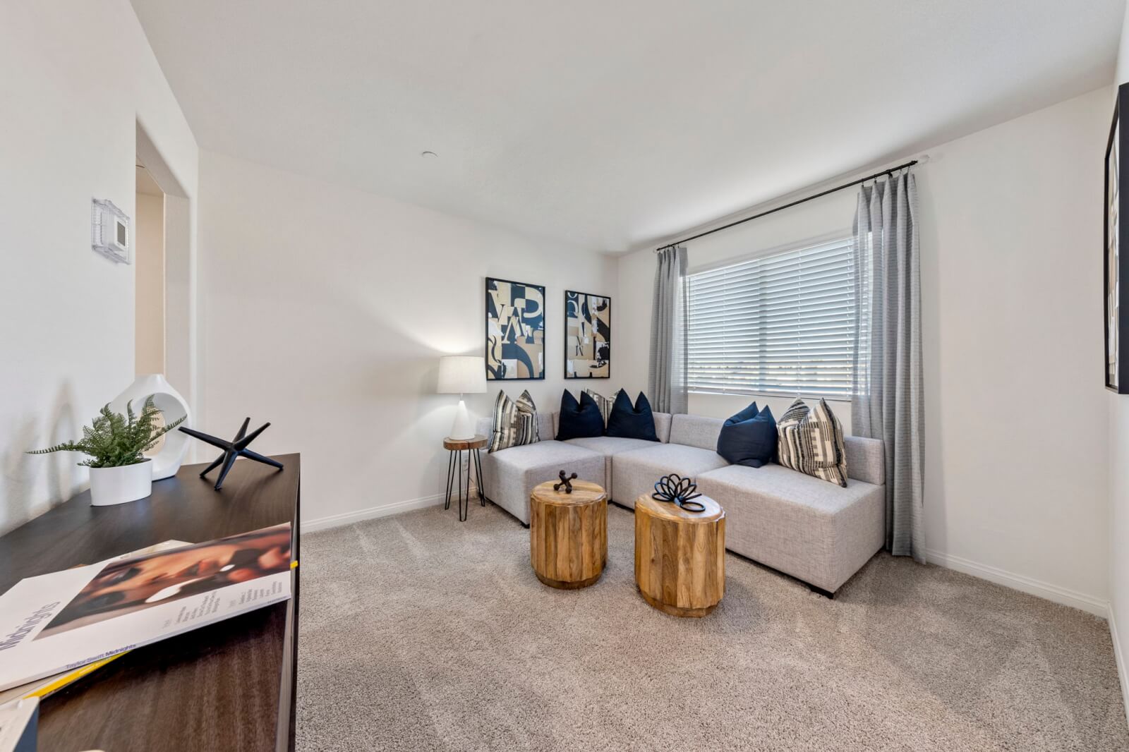 Cozy upstairs loft area staged with a grey sectional sofa and two wooden coffee tables in a Triumph 270 home at the Independence neighborhood.