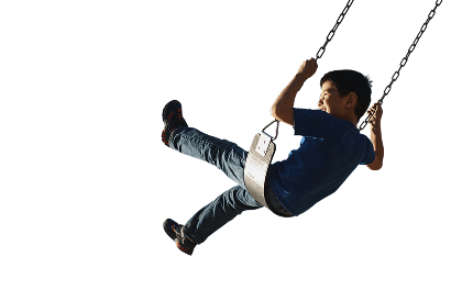 A young boy smiling and laughing while riding a swing at a playground in a Touchstone Living neighborhood.