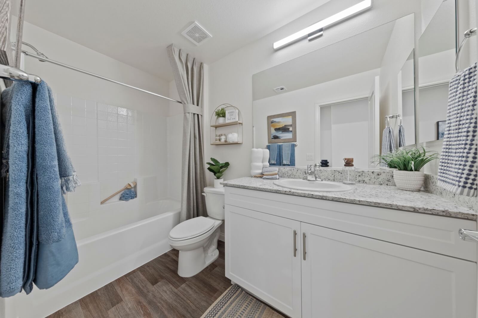 Modern bathroom featuring a white vanity with granite countertops, upgraded vinyl flooring, and a shower and tub combination at the Solaris at Warm Springs neighborhood.