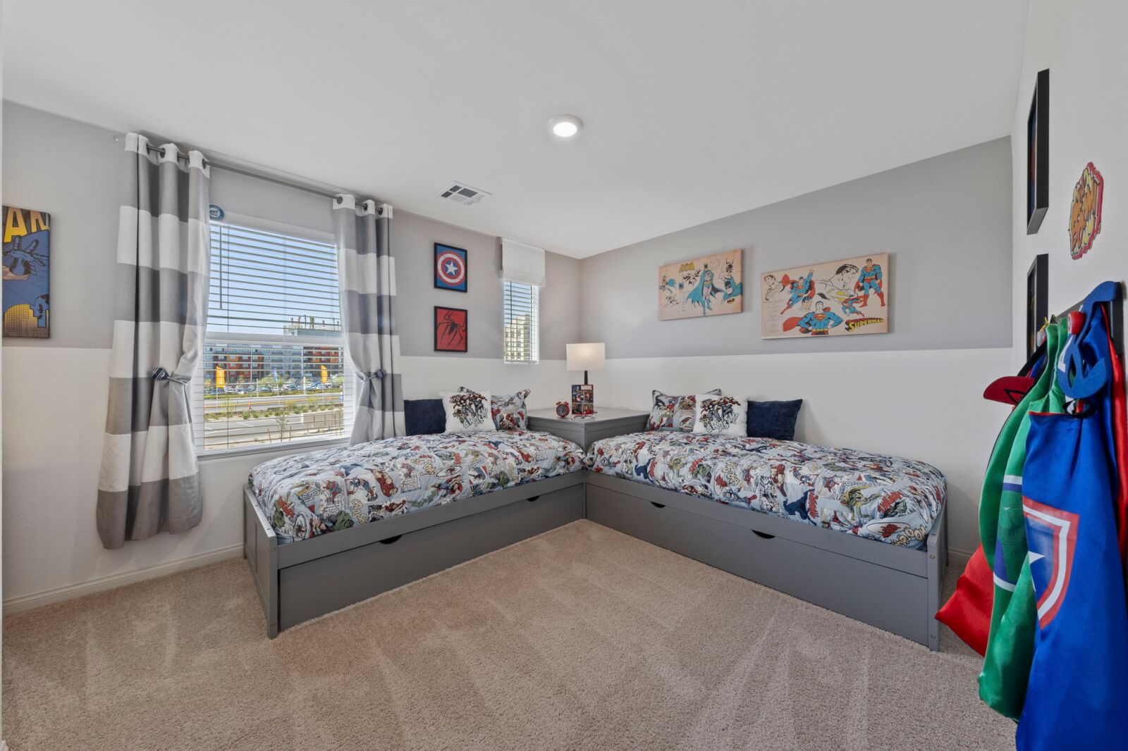Superhero-themed kids bedroom featuring two corner-aligned twin beds with storage drawers in a Solaris model at the Solaris at Warm Springs neighborhood.
