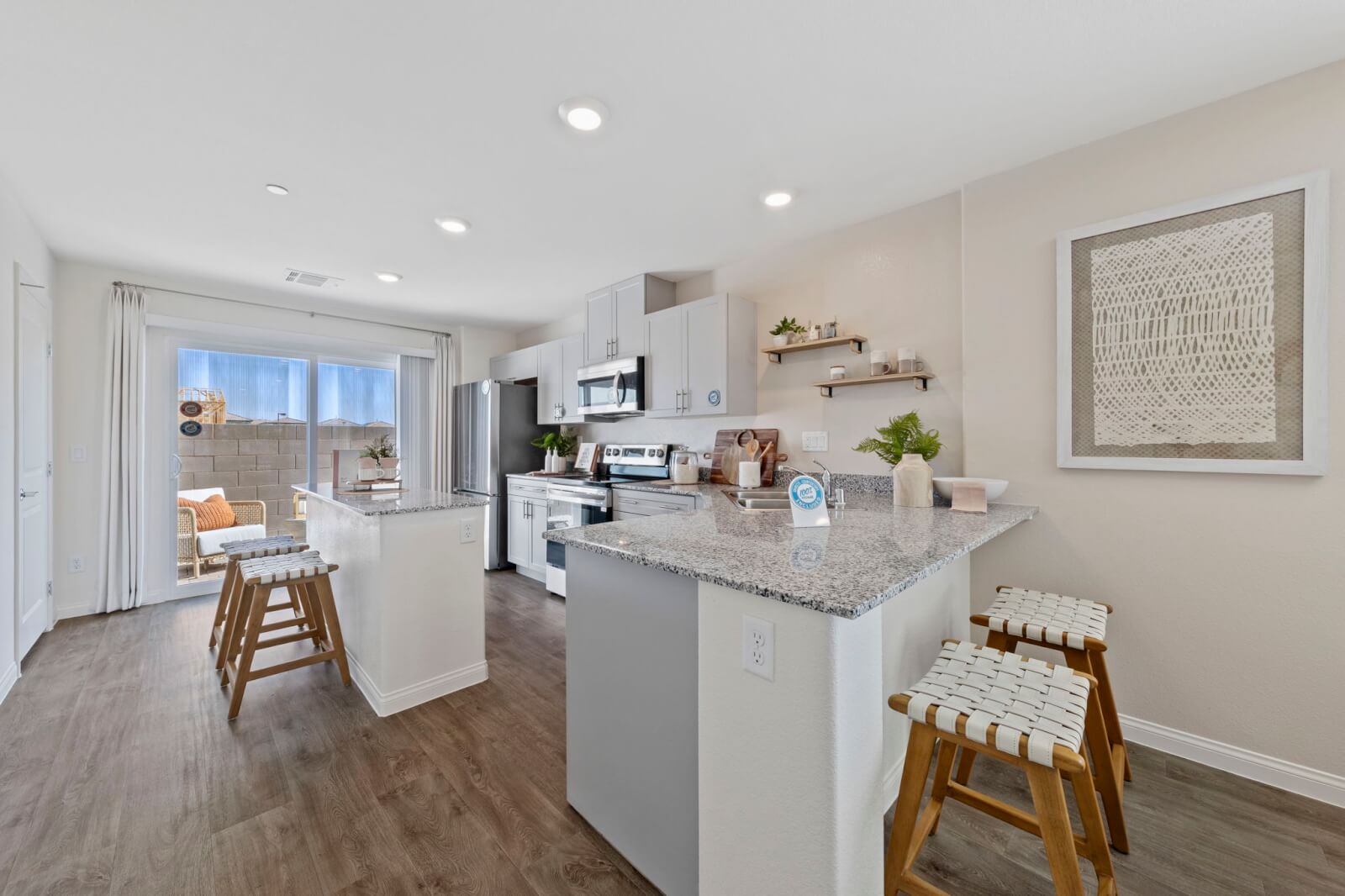 Modern kitchen featuring light grey cabinetry, granite countertops, upgraded vinyl flooring, and stainless steel Samsung® appliances in a Solaris model at the Solaris at Warm Springs neighborhood.
