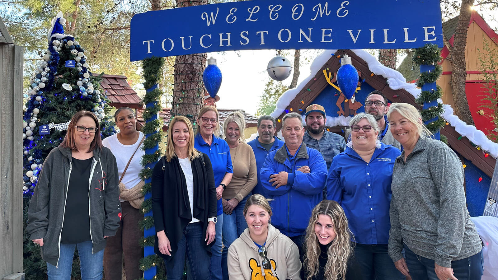 Touchstone Living team members enjoying holiday festivities in an affordable Las Vegas neighborhood. A sign says "Welcome Touchstoneville"