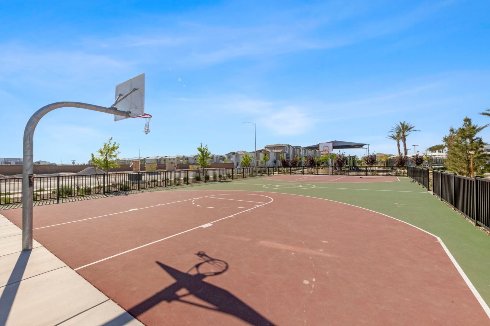 Outdoor basketball court with a red and green painted surface and a metal hoop at the Watercolor planned community.
