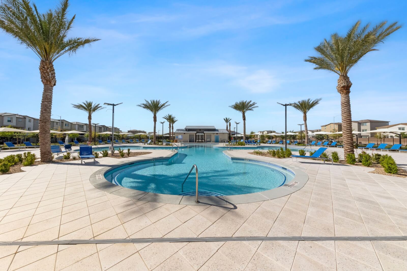 Large, free-form resort-style swimming pool surrounded by palm trees and blue lounge chairs at the Watercolor planned community.