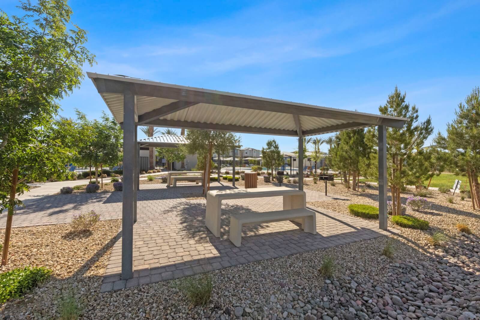Covered picnic pavilion with a concrete table and benches surrounded by desert landscaping at the Watercolor planned community.