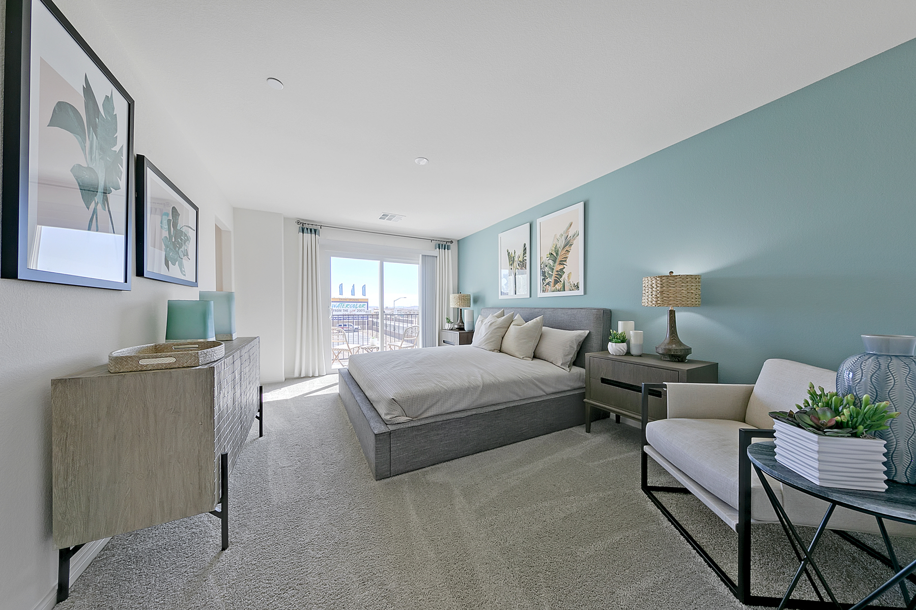 Primary bedroom featuring a light blue accent wall, a grey upholstered bed, a grey textured dresser, and a sliding glass door in a Crimson Plan 524 model home.