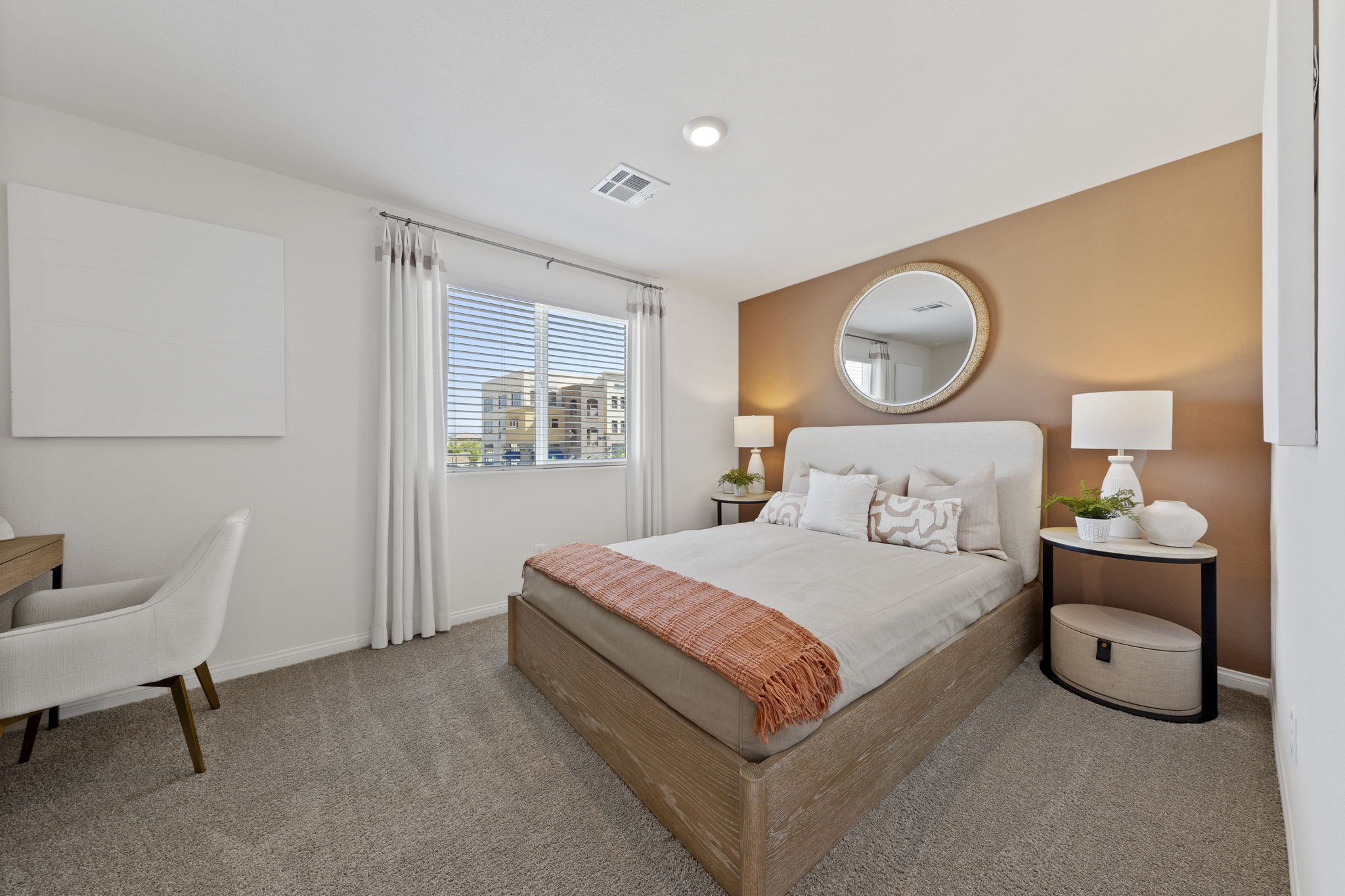Secondary bedroom featuring a terracotta accent wall, a light wood bed with a rust-orange throw blanket, and a dedicated desk area in a Solaris model home.