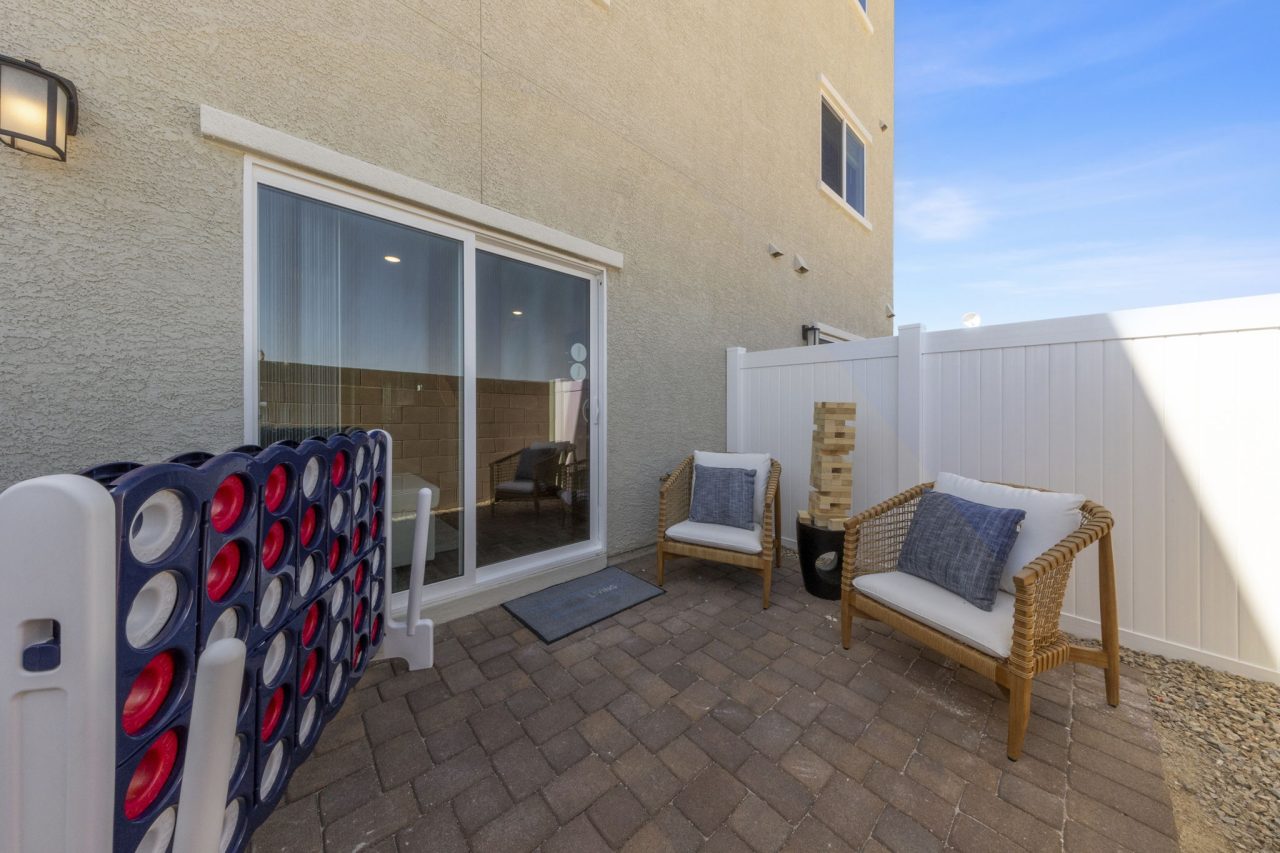Private enclosed backyard patio featuring brick pavers, comfortable seating, and giant outdoor games at a Solaris home.