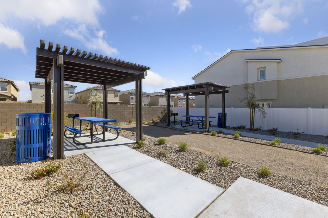 Shaded outdoor picnic pavilions with blue tables and built-in barbecue grills at the Solaris new home community.