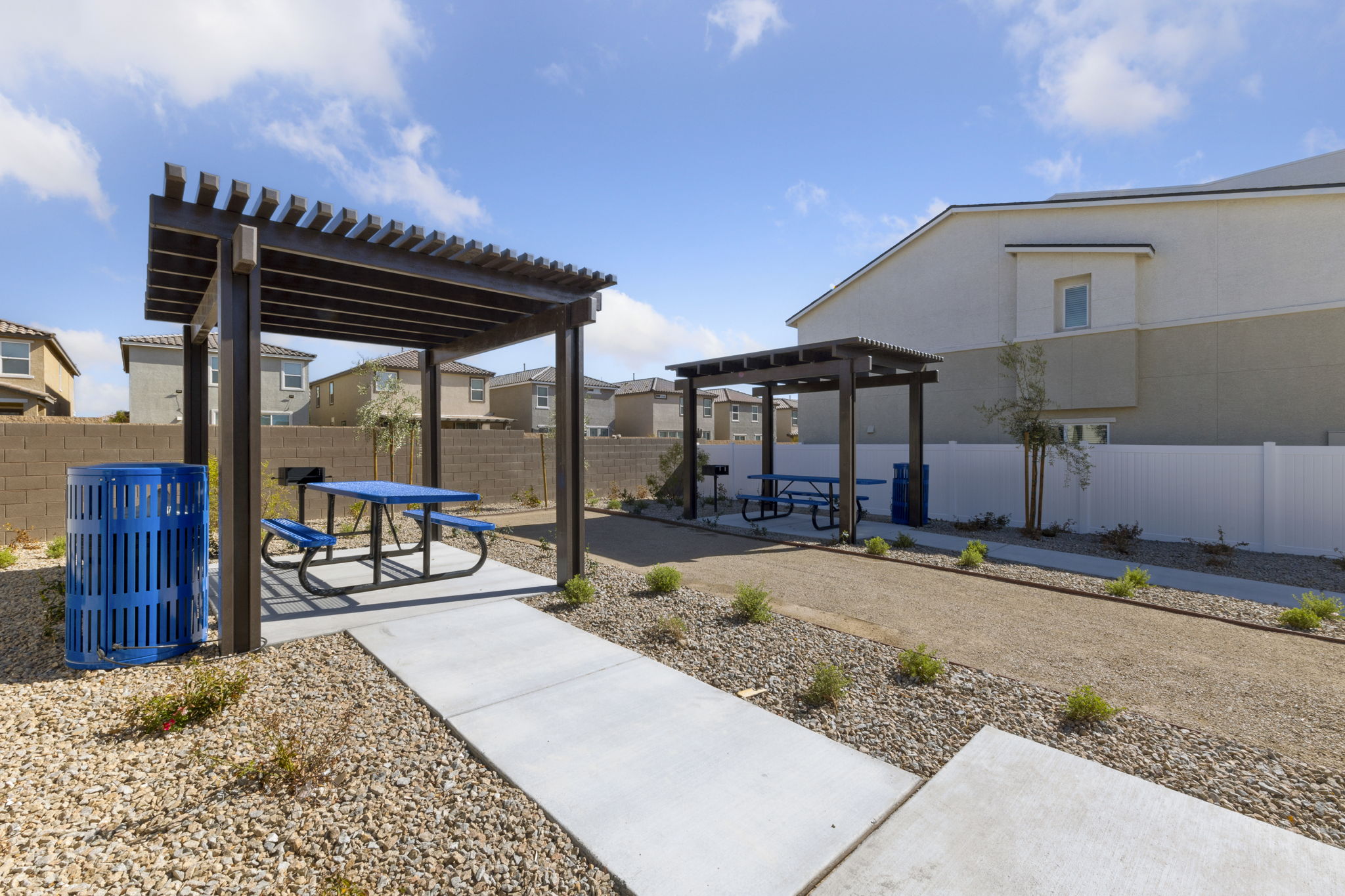 Shaded outdoor picnic pavilions with blue tables and built-in barbecue grills at the Solaris new home community.