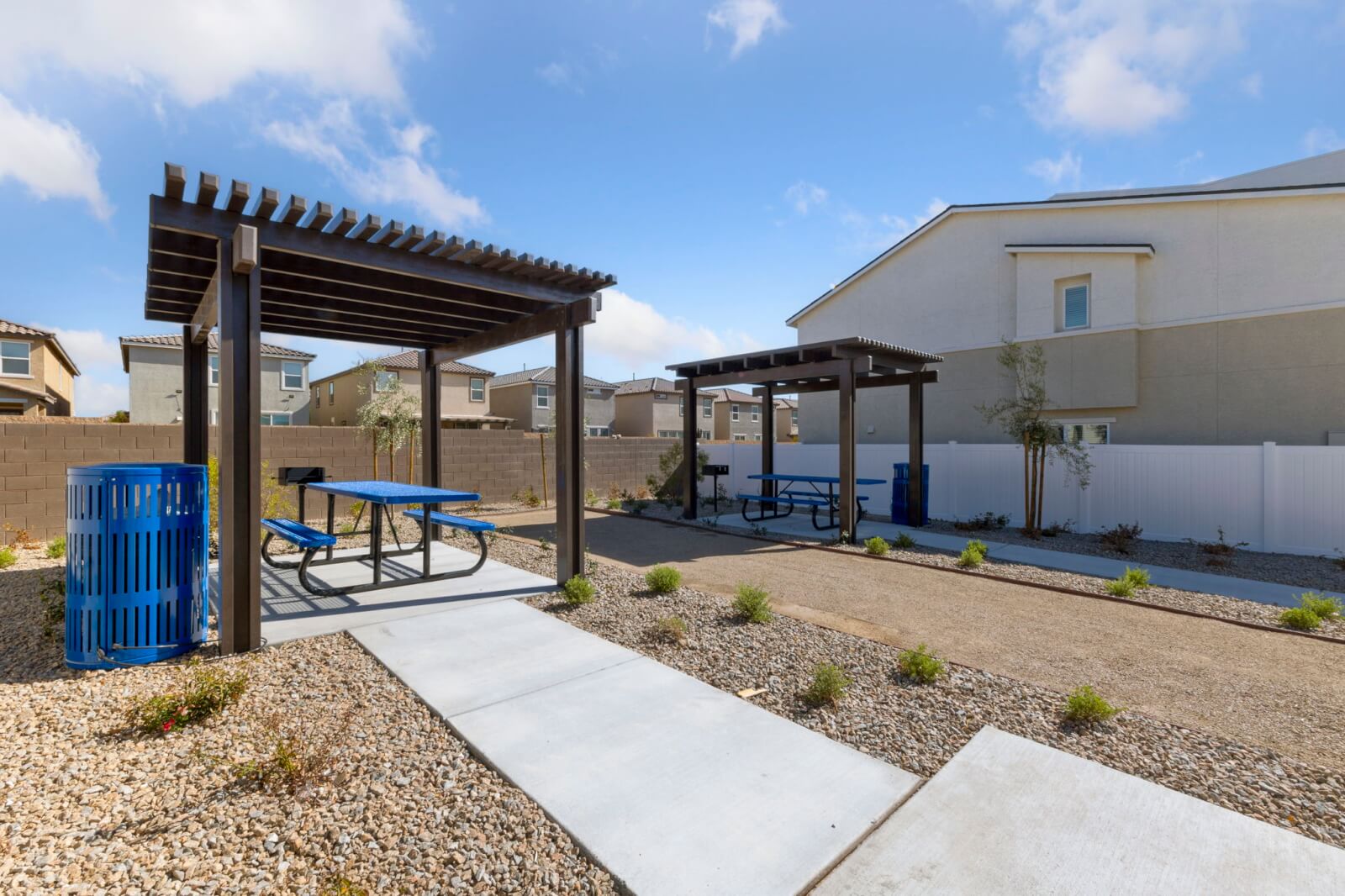 Shaded outdoor picnic pavilions with blue tables and built-in barbecue grills at the Solaris new home community.