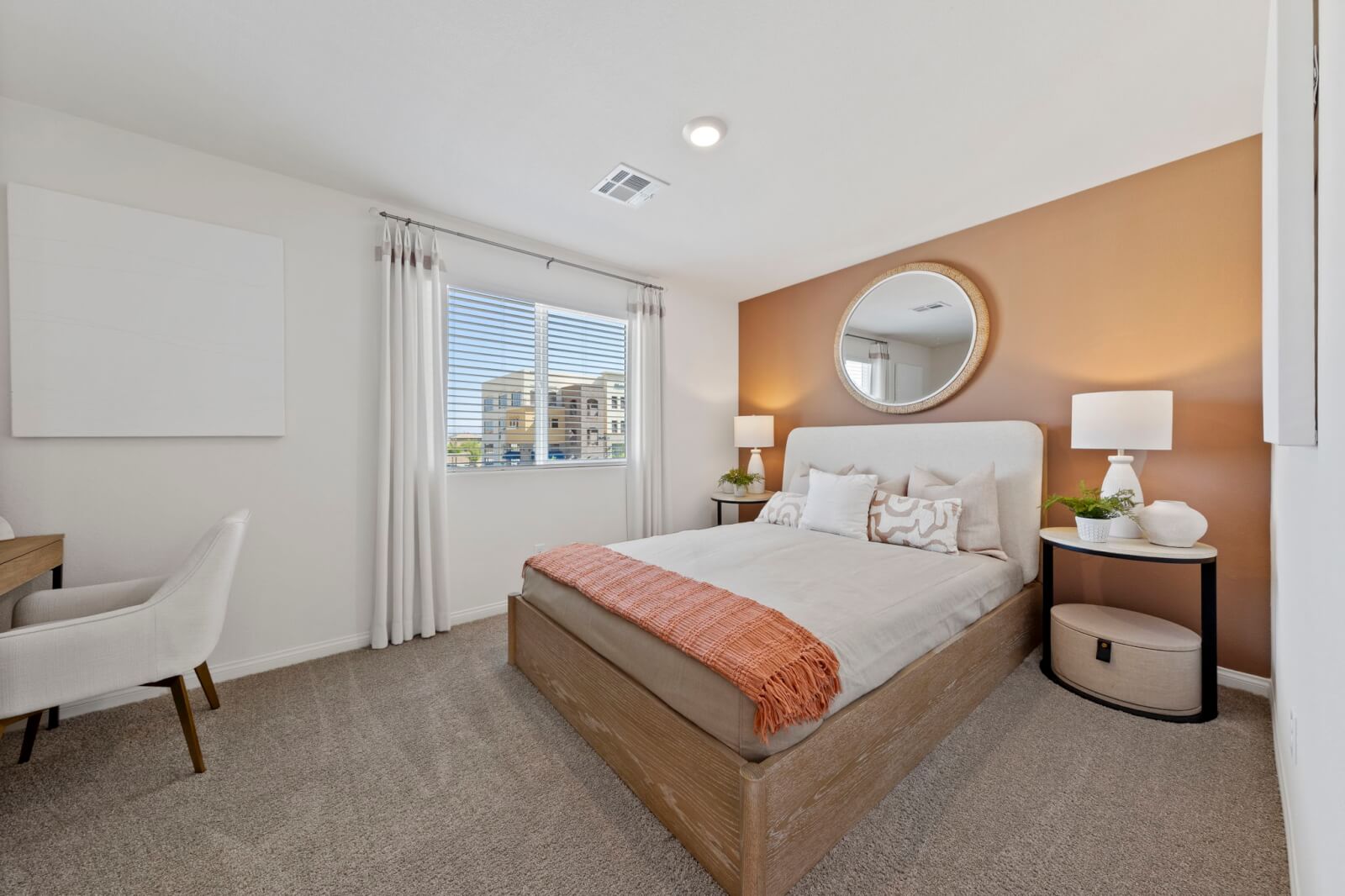 Secondary bedroom featuring a terracotta accent wall, a light wood bed with a rust-orange throw blanket, and a dedicated desk area in a Solaris model home.
