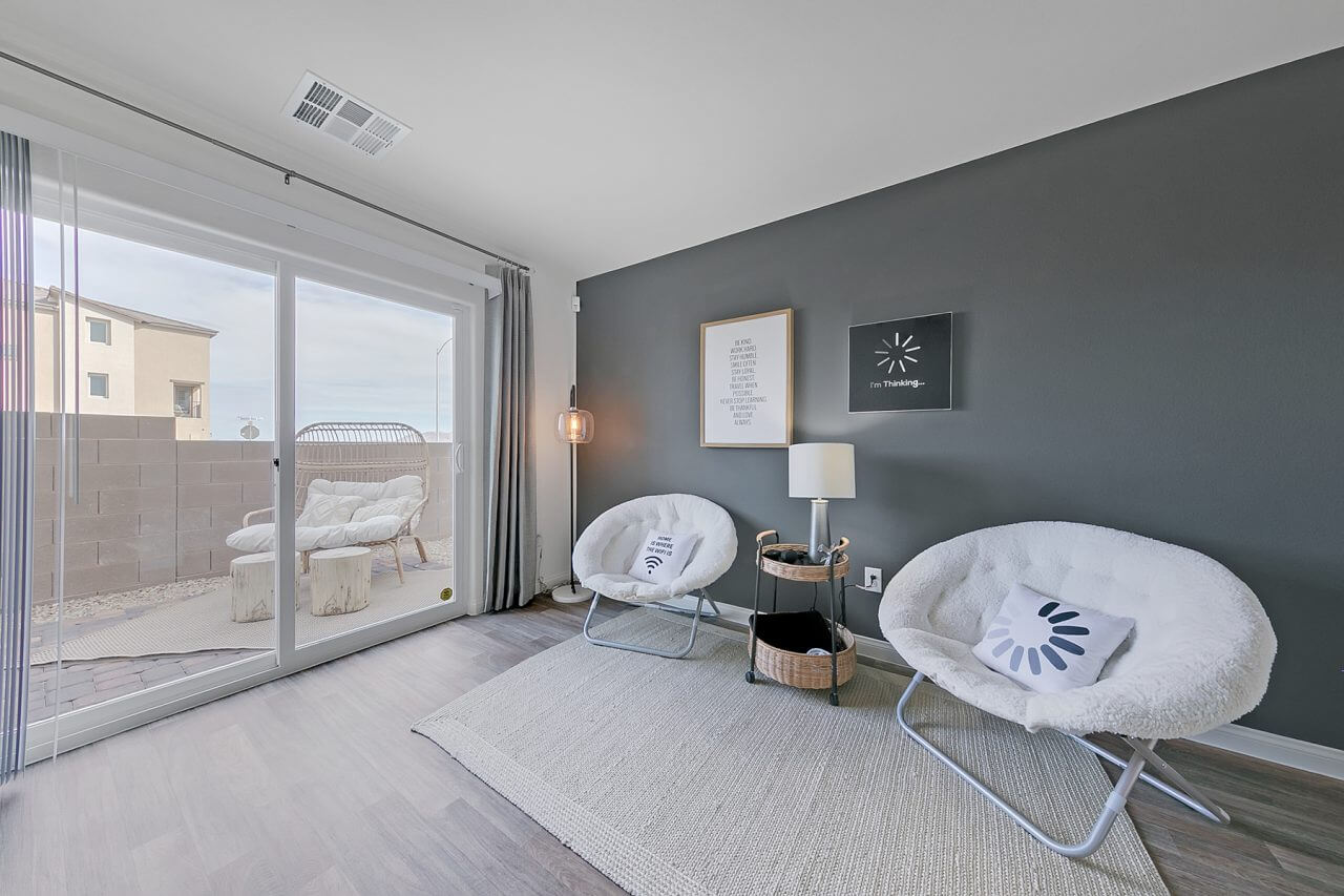 Indigo Plan 544 bonus room lounge with a grey accent wall and white saucer chairs inside a Touchstone Living townhome at the Watercolor neighborhood in North Las Vegas.