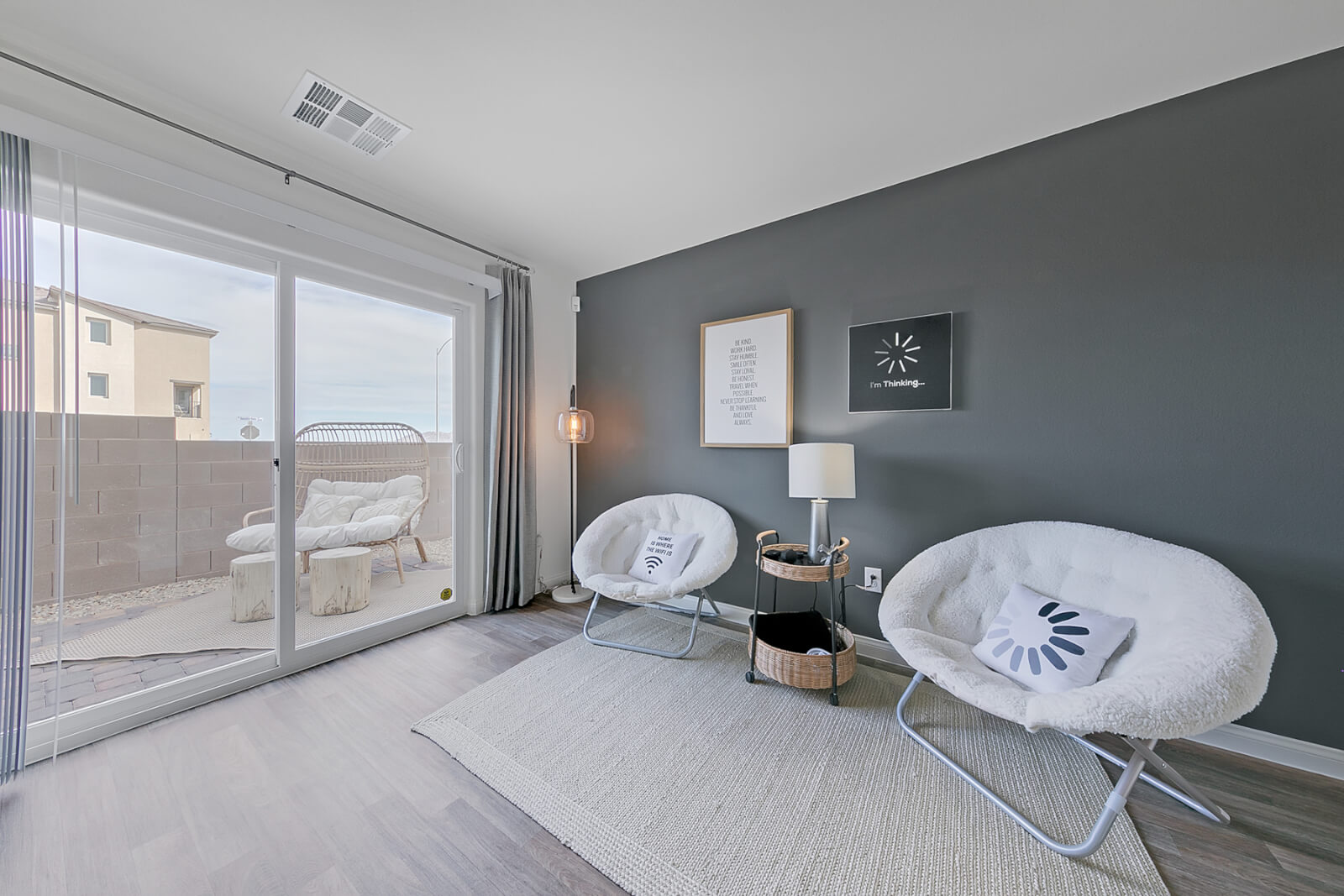 Indigo Plan 544 bonus room lounge with a grey accent wall and white saucer chairs inside a Touchstone Living townhome at the Watercolor neighborhood in North Las Vegas.