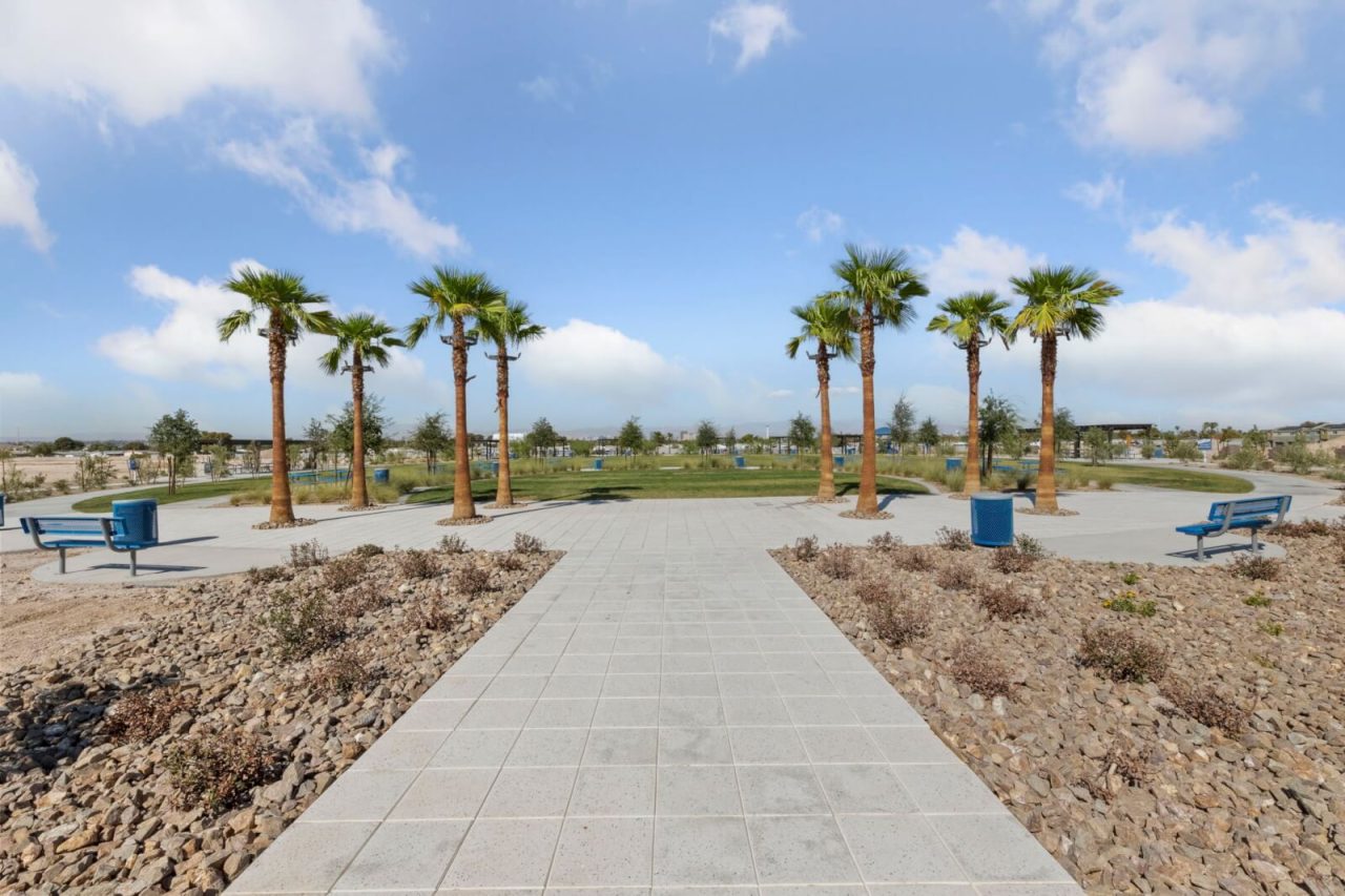 Paved walkway leading into the 5-acre community park with palm trees and green space at the Independence townhome community in East Las Vegas.