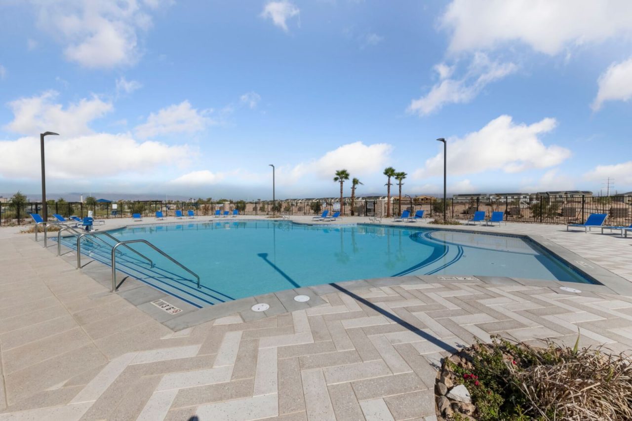 Resort-style swimming pool with shallow entry, blue lounge chairs, and a paved deck at the Independence planned community in East Las Vegas.