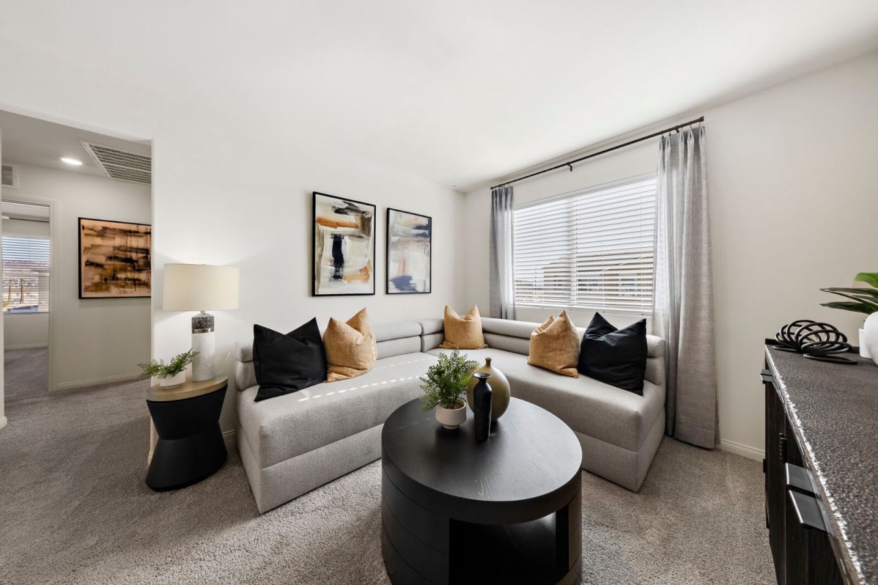 Modern upstairs loft featuring a long grey sofa, a round black coffee table, and contemporary decor in a Touchstone Living home.