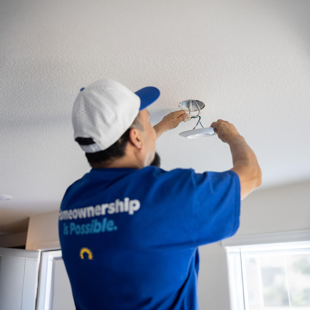 Touchstone repairman fixing a smoke detector on the ceiling.
